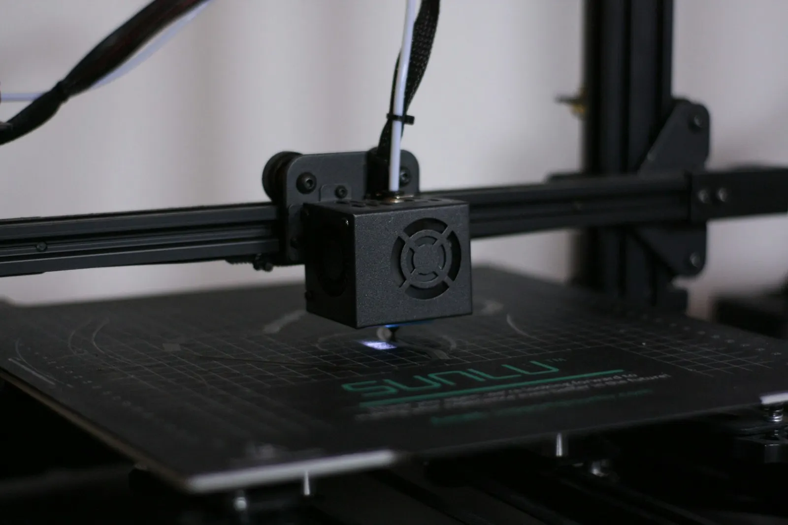 A 3D printer hotend and wiring harness above a magnetic print surface